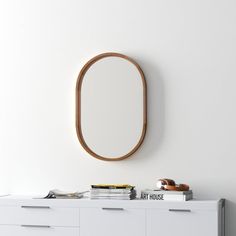 a white dresser with a round mirror above it