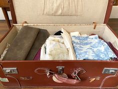 an open suitcase filled with clothes on top of a wooden floor