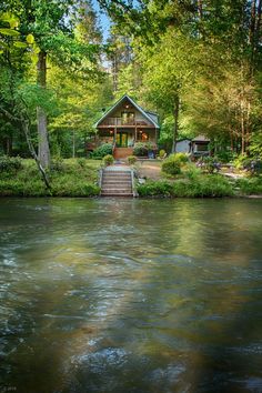 a house sitting on top of a river next to a forest