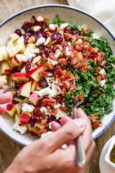 a bowl filled with apples, bacon and other food on top of a wooden table