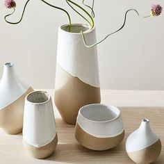 three vases with flowers in them sitting on a table next to each other,