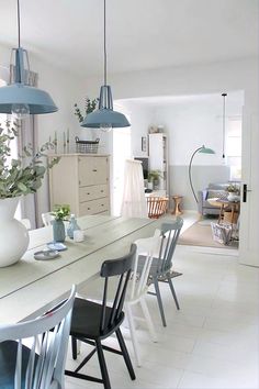 an instagram photo of a dining room table and chairs with blue pendant lights above them