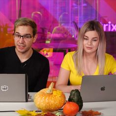 two people sitting at a table with laptops