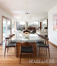 a dining room table with chairs and a fire place in the center surrounded by windows