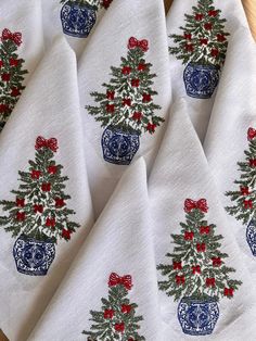 four white christmas napkins with blue and red designs on them, sitting on a wooden table