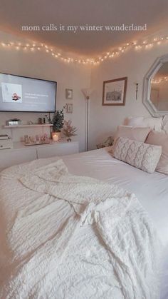 a bedroom with white bedding and string lights on the ceiling, tv mounted to the wall