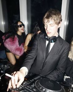 a young man in a tuxedo djs at a party