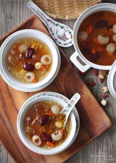 three bowls filled with soup on top of a wooden tray