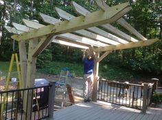 a man standing under a wooden structure in the woods