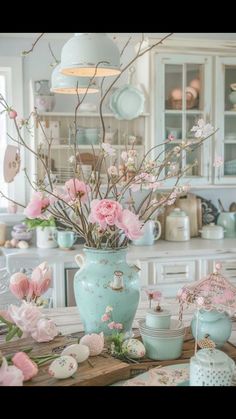 a vase filled with pink flowers sitting on top of a table next to plates and cups