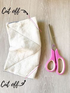 a pair of pink scissors sitting on top of a piece of fabric next to some scissors