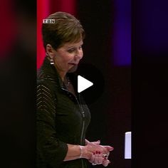 a woman is standing in front of a screen and talking to someone on the stage