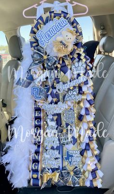 the back seat of a car decorated with blue and gold ribbons, white feathers, and a teddy bear