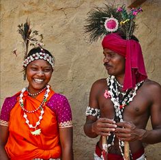 two people standing next to each other wearing headdresses and feathers on their heads