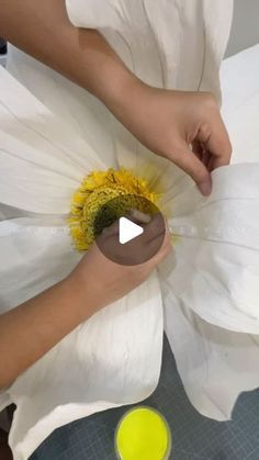 someone is painting a large white flower with yellow paint