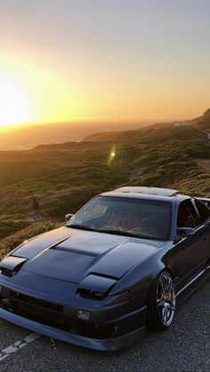 the car is parked on the side of the road by the ocean at sunset or sunrise