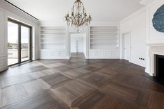 an empty room with white walls and wood flooring, chandelier hanging from the ceiling