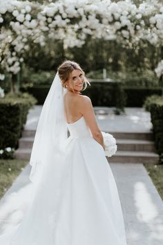 a woman in a wedding dress is standing outside