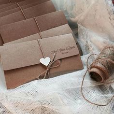 several brown envelopes tied with twine on a white table cloth and some yarn