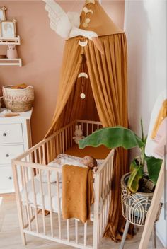 a baby's crib with a canopy over it and a bird hanging from the ceiling