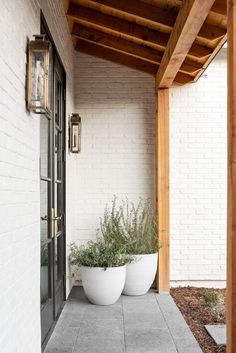 two large white planters sitting on the side of a building next to a door