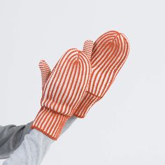 an orange and white striped oven mitt being held up in the air