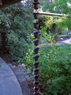 a tall tower made out of wine bottles sitting on top of a stone walkway next to a lush green forest