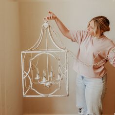 a woman holding up a white bird cage