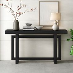 a black table with two vases and a lamp on it next to a potted plant