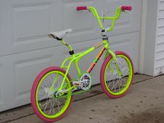 a yellow and pink bike parked in front of a garage door