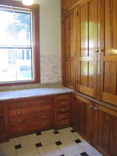 a kitchen with wooden cabinets and black and white checkered flooring on the tile