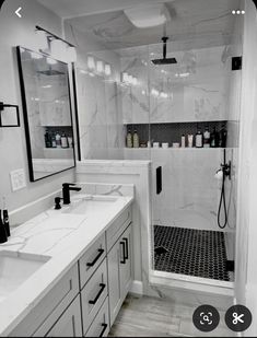 a white bathroom with marble counter tops and black accents on the shower wall, along with two sinks