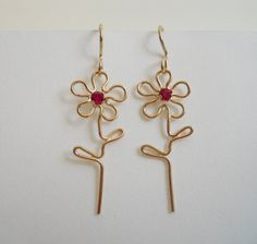 two pairs of gold earrings with red stones in the shape of flowers on white background