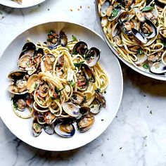 pasta with clams and parmesan bread on a marble countertop next to two bowls