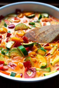 a white bowl filled with vegetables and a wooden spoon on top of the soup in it