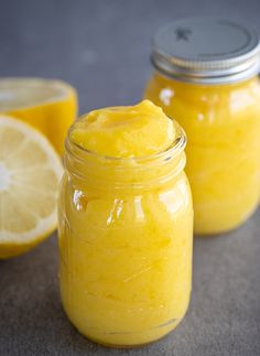 two jars filled with yellow liquid next to lemons