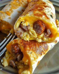 two breakfast burritos on a plate with a fork