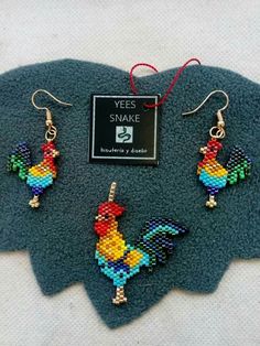 three pieces of beaded jewelry sitting on top of a blue piece of cloth next to a pair of earrings