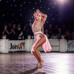 a woman in a pink dress is dancing on the dance floor with her arms up