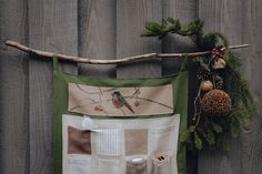 a piece of fabric hanging on a wooden fence with pine cones and other items around it