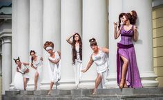 a group of women dressed in white and purple posing on steps with their hands behind their heads