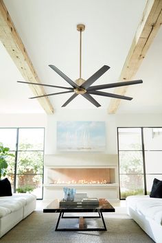 a living room with a large ceiling fan in it's centerpiece and two white couches