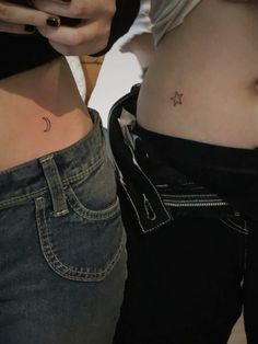 two women with small tattoos on their stomachs, one is holding a cell phone