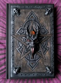 an intricately decorated metal box with skulls on the front and sides, sitting on a purple background