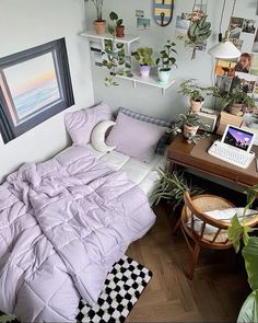 a bedroom with a bed, desk and plants