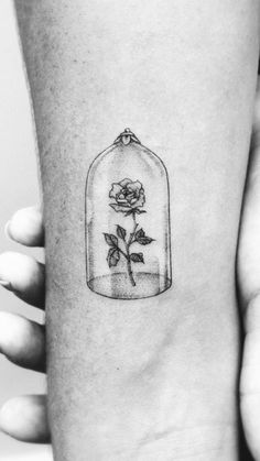 a rose in a glass bottle tattoo on the arm