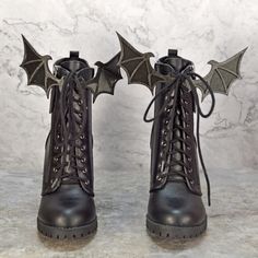 a pair of black boots with bats attached to the side, on a marble surface