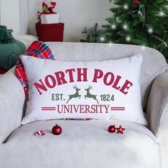 the north pole university pillow is sitting on a chair in front of a christmas tree