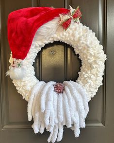 a christmas wreath with santa claus's hat on it hanging from the front door