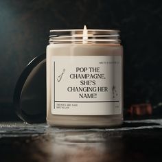 a candle is sitting on a table with the words pop the champagne she's changing her name